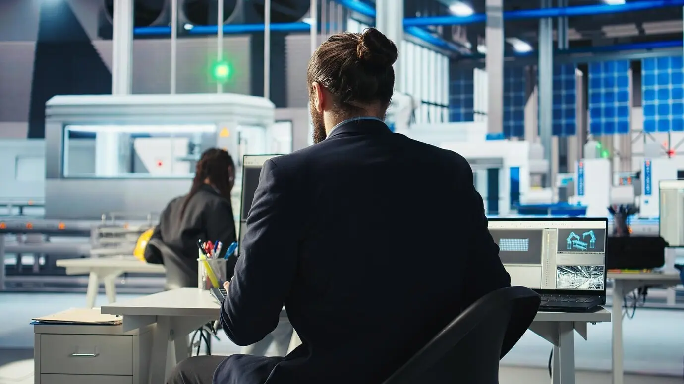 Ingenieur in einer Photovoltaikfabrik nutzt einen Laptop, um die Effizienz von Solarmodulen zu verbessern.